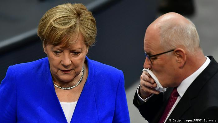 Heads bowed, Kauder (R), with a white hankerchief over his mouth consults with Merkel in the Bundestag chamber (Getty Images/AFP/T. Schwarz)