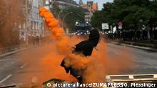 July 7, 2017 - Hamburg, Germany - A protester is throwing an orange smoke flare at a line of German police men...Another day of protests in Hamburg after a night of clashes and mass demonstrations against the G20 summit in the city. July 7, 2017 |