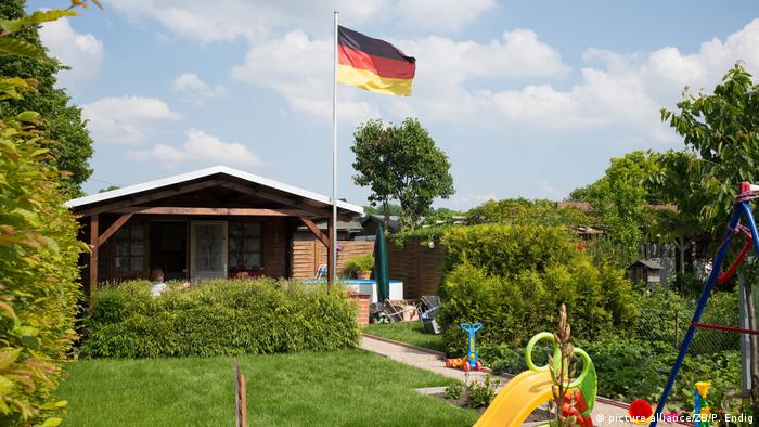 A German flag flutters in a small hobby garden