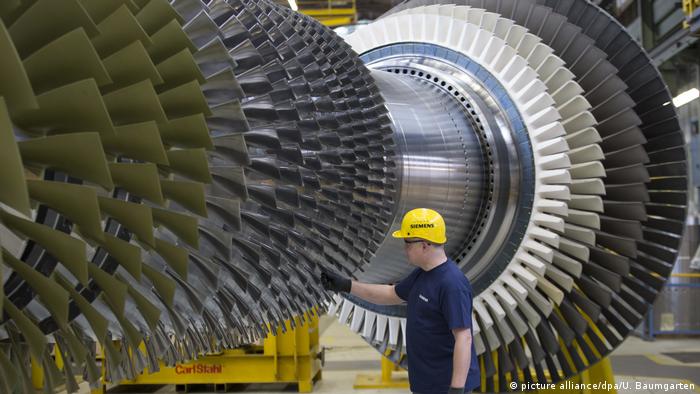 A worker at a Berlin plant in front of a Siemens gas turbine 