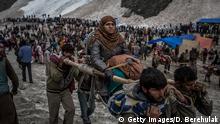 BALTAL, INDIA - JUNE 29: A Hindu pilgrim is carried on a palanquin by Kashmiri bearers over a glacier on her way to the sacred Amarnath Cave, one of the most revered Hindu shrines, on June 29, 2012 near Baltal, Kashmir, India. Hindu devotees brave sub-zero temperatures to hike over glaciers and high altitude mountain passes to reach the sacred Amarnath cave, which houses an ice stalagmite, a stylized phallus, worshiped by Hindus as a symbol of the god Shiva. More than 700,000 Hindu pilgrims are expected to take part in this year's two-month pilgrimage, according to local officials, causing strain on the environment and political stability of the region, which has long fought for independence from India. (Photo by Daniel Berehulak/Getty Images)