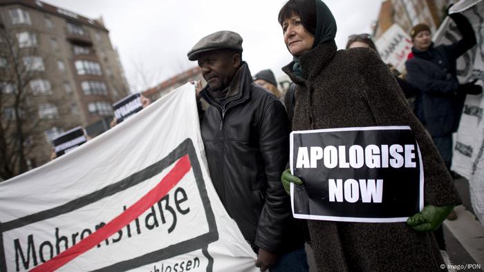 Demonstranten in Berlin mit einem Plakat mit der Auschrift Apologise now