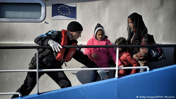 A coastguard helps migrant children disembarking from a Bulgarian FRONTEX ship at the port in Mytilene, on the Greek island of Lesbos after crossing the Aegean sea from Turkey, on February 18, 2016.
