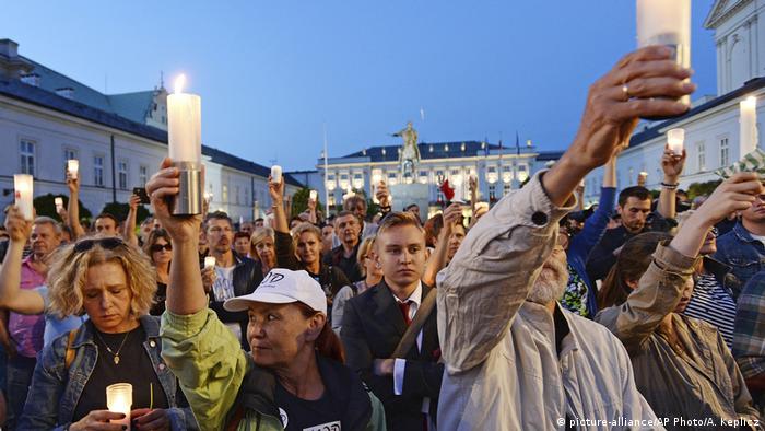 Poles holding up candles at protest in Warsaw