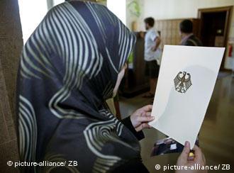 Eine Frau mit Kopftuch hält das Dokument in der Hand: Endlich Deutsche - die Einbürgerungsurkunde machts möglich (Foto: dpa/Archiv)