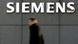 A man in black walking past the Siemens logo A man in black walking past the Siemens logo