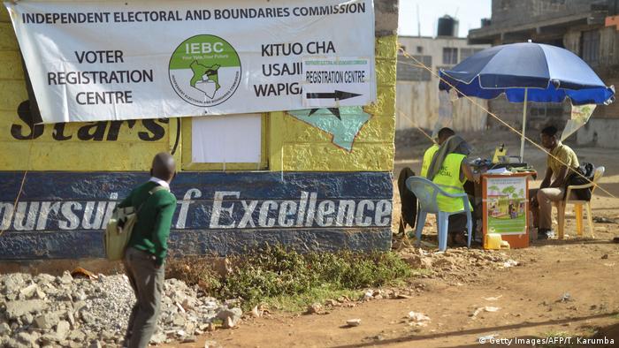 A school boy walks past a banner advert showing a voter registration center in Kenya.
