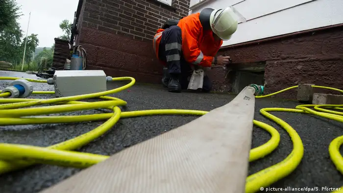 Ein Feuerwehrmann hockt an einem Kellerfenster, in das ein Schlauch zum Wasserabpumpen führt. (Foto: picture-alliance/dpa/S. Pförtner)