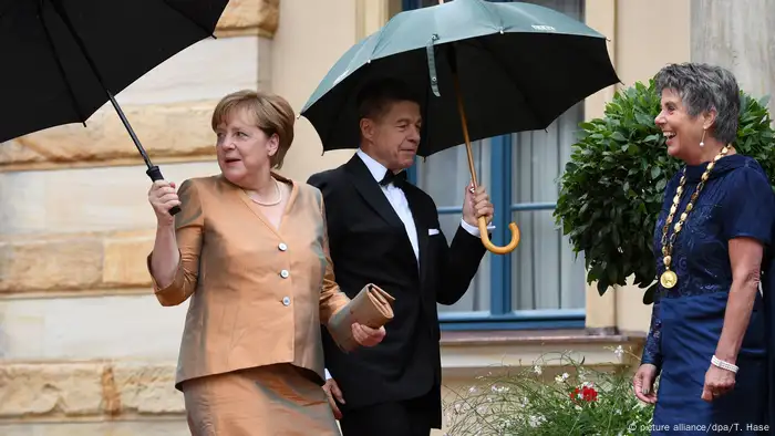 Zum Kleid passend trug die Kanzlerin außerdem eine bronzefarbene Clutch. Ehemann Joachim Sauer, der nur selten mit seiner Frau in der Öffentlichkeit auftritt, schlüpfte in einen klassisch schwarzen Anzug mit Fliege. Angela Merkel ist erklärter Opern-Fan und Wagner-Liebhaberin. 
