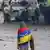 Протестувальник, загорнутий у прапор Венесуели, стоїть у Каракасі навпроти поліцейських