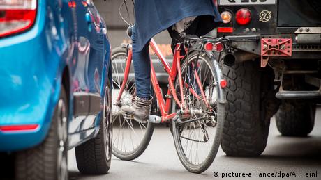 Велосипедист у Берліні лавірує на дорозі між двома автомобілями