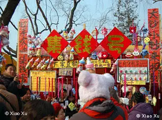 DSC_1201: Ein Händler hängt ein interessantes Reimpaar (Duilian) auf seinen Verkaufsstand. Er wünscht sich, viele Geld zu verdienen für das neue Jahr. Das Bild wurde von Xiao Xu am 29.01.2009 in Peking aufgenommen.