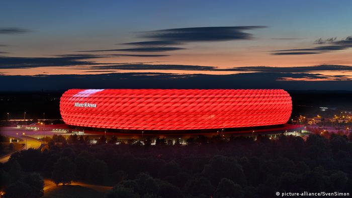 Rot beleuchtete Außenhülle der Münchener Arena mit Abendhimmel