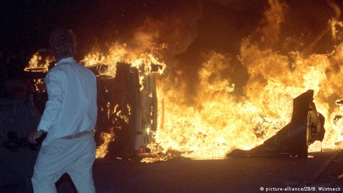 Ausschreitungen Rostock Lichtenhagen 1992 - ein Fahrzeug steht in Flammen