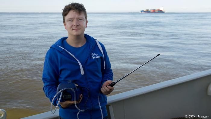 Portrait of Sönke Diesener (NABU) on board the Ryvar holding a device that measures particulate emissions