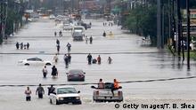 TOPSHOT - People walk through the flooded waters of Telephone Rd. in Houston on August 27, 2017 as the US fourth city city battles with tropical storm Harvey and resulting floods. / AFP PHOTO / Thomas B. Shea (Photo credit should read THOMAS B. SHEA/AFP/Getty Images)
