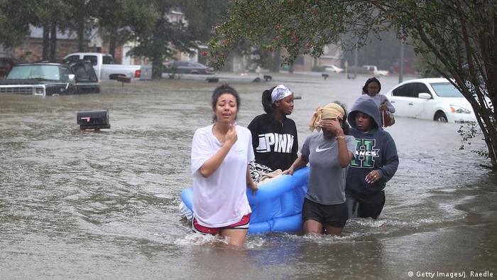 People wading down a flooded street as they evacuate their homes after flooding from Hurricane Harvey on August 28, 2017 in Houston, Texas