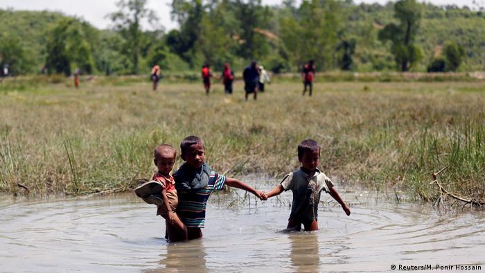 Rohingya children make their way through water 