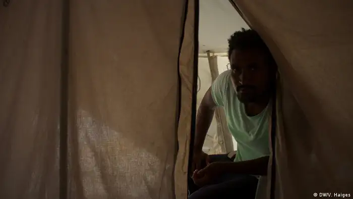 An Ethiopian asylum-seekers peers out of a tent in Lesbos