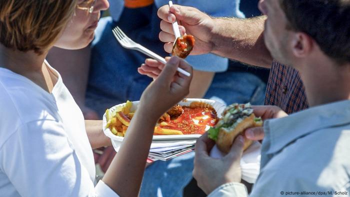 Eine Frau und ein Mann essen Fast Food (picture-alliance/dpa/M. Scholz)