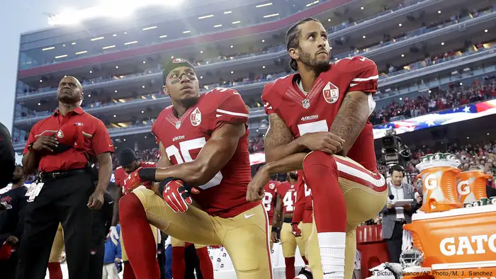 San Franciso 49ers Eric Reid and Colin Kaepernic take a knee during a national anthem performance before a football game in a stadium (picture-alliance/AP Photo/M. J. Sanchez)