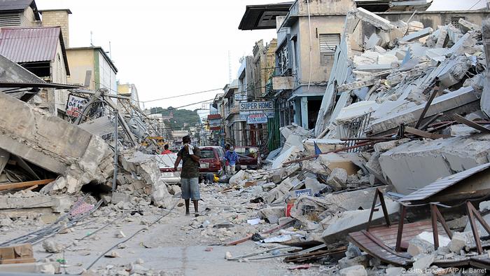 Ein Mann steht in einem Straßenzug mit eingefallen Häusern rechts und links - nach Erdbeben in Haiti 2010