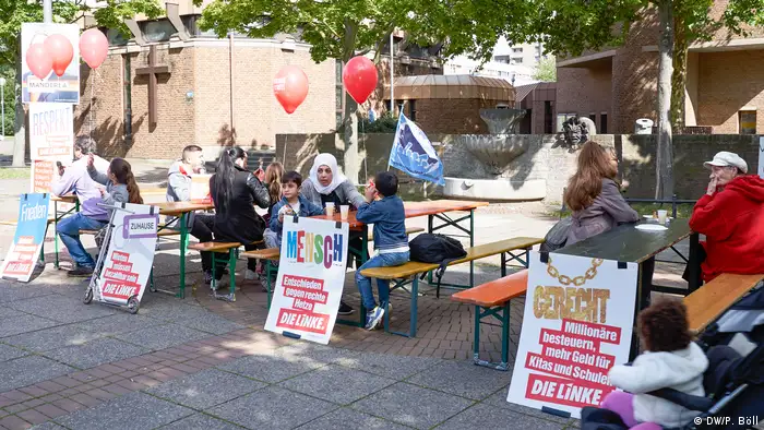 Menschen, die an Bierbänken sitzen, während einer Wahlkampfveranstaltung der Partei Die Linke (Foto: DW/P. Böll)