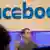 Mark Zuckerberg gestures during a speech with the Facebook logo behind him