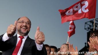 Schulz gives thumbs up at a campaign rally under an SPD flag