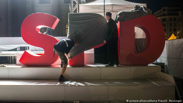 workers covering up the SPD logo at an election campaign event