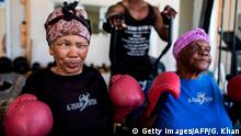 77 year-old Gladys Ngwenya (L) winces as she chews on a piece of ginger before a Boxing Gogos (Grannies) session hosted by the A Team Gym in Cosmo City in Johannesburg on September 19, 2017.
The grandmothers, many of whom are over 70 have been training with coach Claude Maphosa and claim that they no longer suffer from the ailments they had before, and are stronger than ever. The grannies travel from all over Cosmo City for the twice weekly sessions. Coach Maphosa is in the process of planning events in other areas for grannies who have been inspired by the story, to join in. / AFP PHOTO / GULSHAN KHAN (Photo credit should read GULSHAN KHAN/AFP/Getty Images)