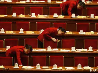 Chinese ushers looks under the tables after delegates leave at the end of the opening session of the Chinese People's Political Consultative Conference held at the Great Hall of the People in Beijing, China,Tuesday, March 3 , 2009. Economic troubles, including creating jobs and ensuring a massive stimulus package is properly used, are the main concerns for China's main legislative advisory body meeting this week. (AP Photo/Ng Han Guan)