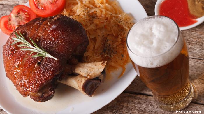 Baked pork shank and sauerkraut closeup on a plate and beer on the table.