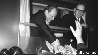 Kurz vor der Abfahrt vom Erfurter Hauptbahnhof am 19.3.1970 schüttelt Bundeskanzler Willy Brandt (l.) aus einem Zugfenster heraus unzählige Hände