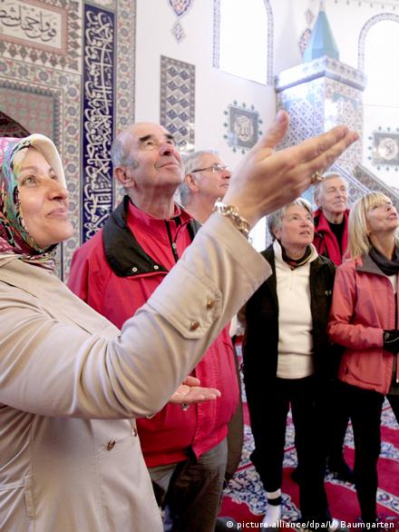 People gaze at the prayer room of a mosque in Hürth