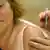 Women receiving a flu shot. Hand holding needle.