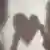 Shadows of a woman and a man holding a heart between them