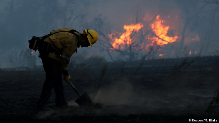 A firefighter works to put out hot spots