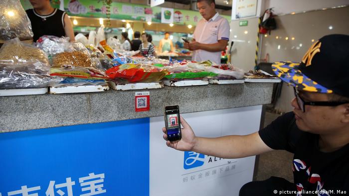 A Chinese shopper paying with a mobile phone in a store