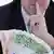 Мужчина держит в руках пачку купюр в 100 и 50 евро, приложив указательный палец к губам