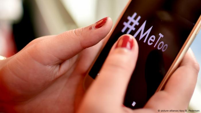 Hand holding phone with #MeToo hashtag written on the screen