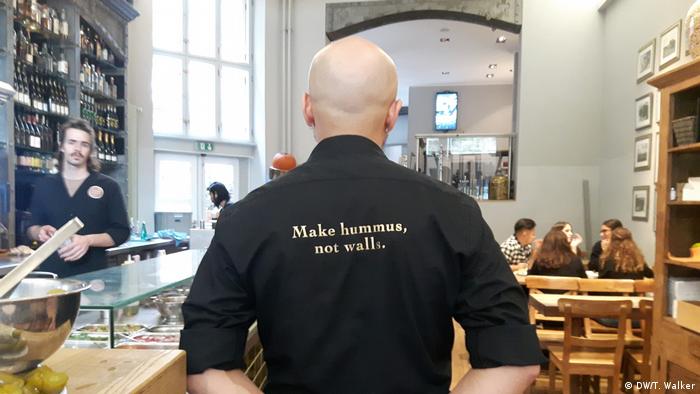 A man wearing a shirt that reads make hummus, not walls