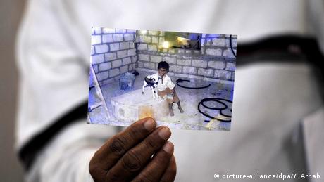 A Yemeni man holds a photo of a child who allegedly died after being injured in a drone strike