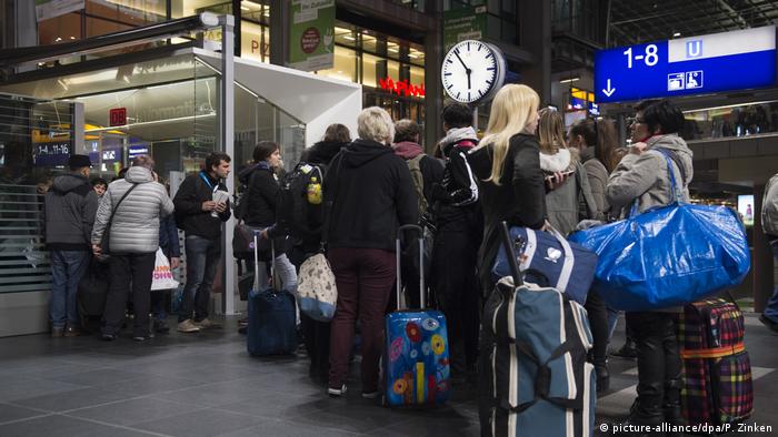 Lines of people wait outside a Deutsche Bahn service point at Hamburg's main train station following Storm Herwart