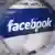 Facebook logo seen through a magnifying glass