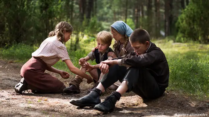 Children sit in the woods in scene from the 2012 movie Wolfskinder