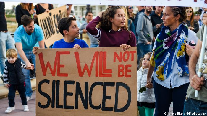 Maltese hold signs to protest the murder of journalist Daphne Caruana Galizia