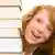 Junge rotharige lächelnde Frau mit Bücherstapel (Foto: picture-alliance / chromorange)