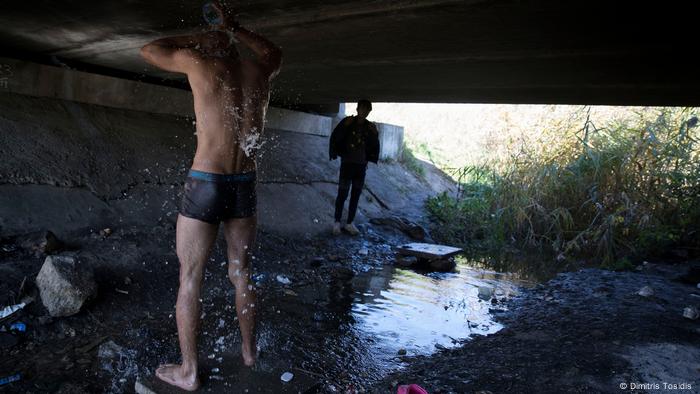 Ein Mann in Badehose kippt sich unter einer mit einem Tiegel Wasser über den Kopf