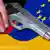 Коллаж, на котором на фоне флагов ЕС и Германии изображена рука с пистолетом